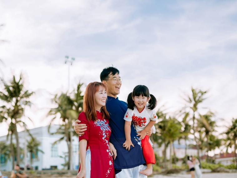 A family standing together outdoors, laughing at something off to one side.